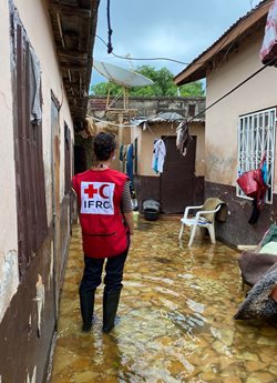 Sarah Parisio wearing a Red Cross vest and looking at flooding devastation