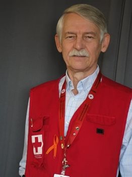 A man standing in front of a dark background with a Canadian Red Cross vest on