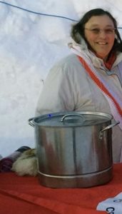 Red Cross volunteer Bobbi Montean standing behind a table with a large soup pot on it.