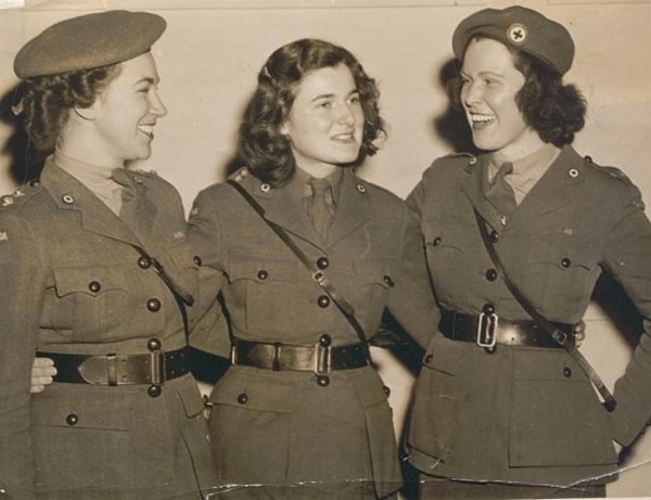 A black and white archived photo of three women standing in Red Cross uniforms smiling