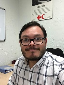 Juan sitting at a desk smiling.