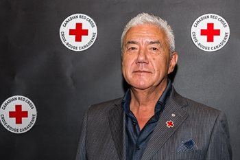 Tom Jackson standing in front of Canadian Red Cross backdrop.