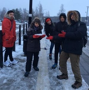 A group of people outside in wintertime holding snow
