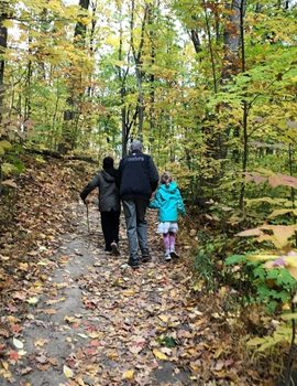 A man and two kids walking through a forest at fall time