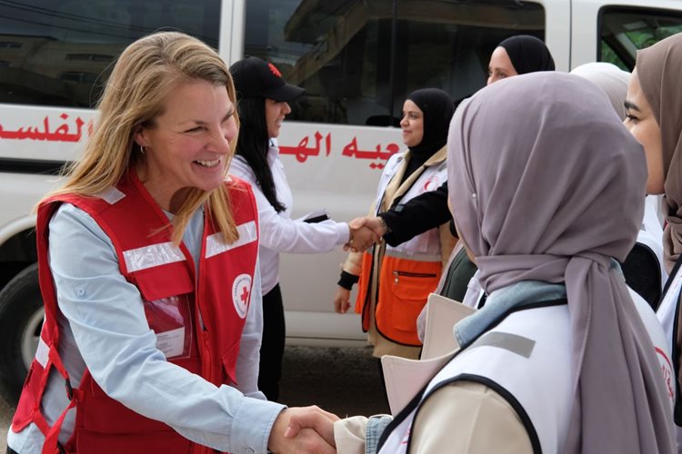 Kelsey Lemon smiling while shaking the hand of a Palestine Red Crescent Society volunteer.
