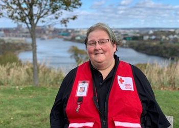 Cheryl Horgan pictured outside in her Canadian Red Cross vest standing by a body of water.