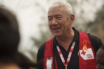 Tom Jackson in a Red Cross vest smiling at people.