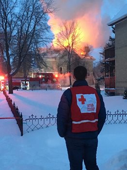 A member of the Red Cross standing by a house fire