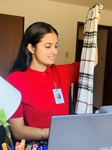 Bavleen Kaur holding up a scarf in front of a laptop