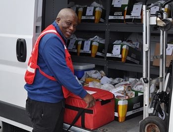 A man lifting boxes of supplies from a white van