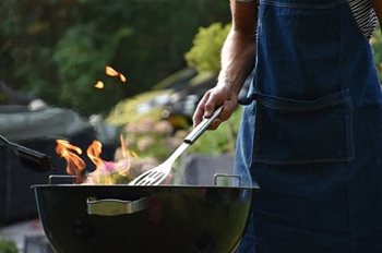 Person in an apron with a spatula at a bbq