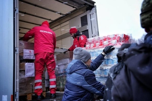 People in Red Cross jackets unloading supplies from a large truck