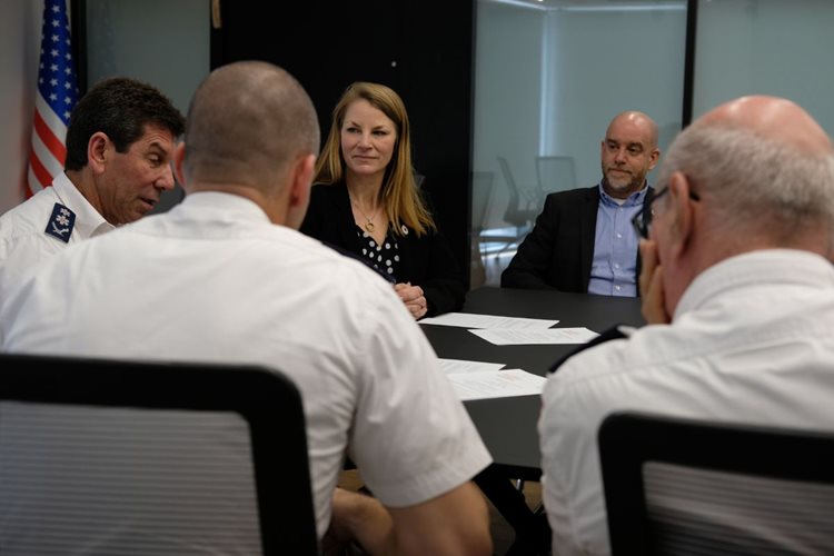 Kelsey Lemon and four other people seated around a table in a board room.