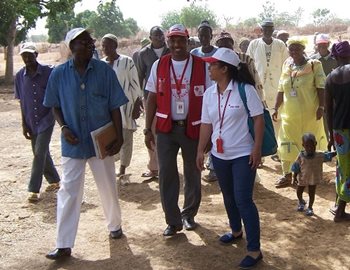 Jules smiling at other people in Red Cross vests, walking with a group of local residents