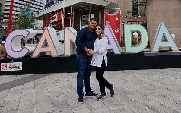 A man and a woman embracing in front of a Canada sign