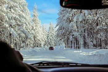 A car following another car on a wintry, snow-covered road