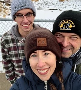 Three people in winter hats crowd together for a photo outside