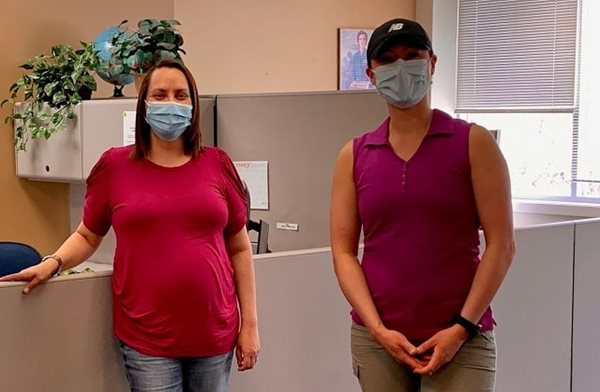 Two women in masks standing in an office