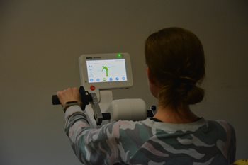 A woman from the back is doing exercices on a medical equipment