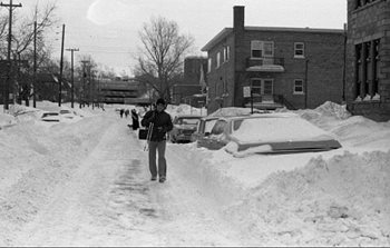 A man walking down a snow-covered road after a bad storm in Quebec